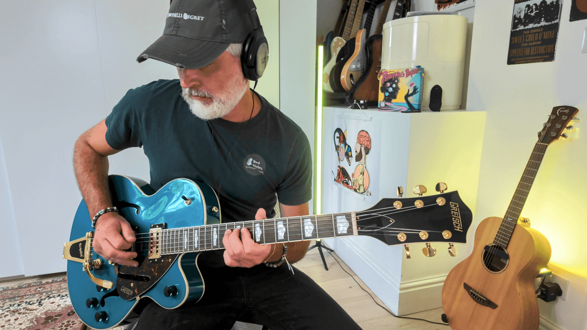 Person playing a blue electric guitar while wearing headphones, with guitars and music posters in the background.